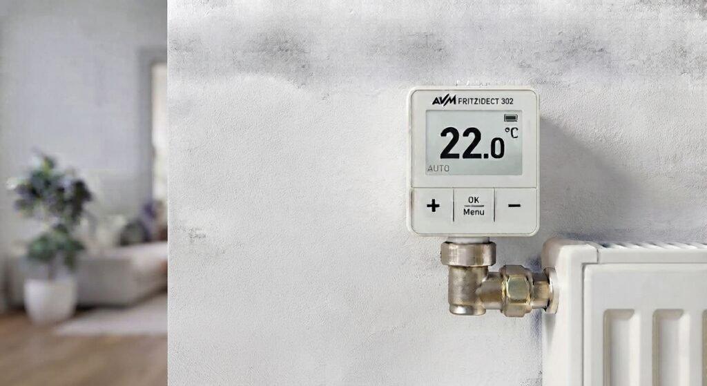 Detailansicht des montierten smarten Heizkörperthermostats AVM FRITZ!DECT 302 mit E-Ink Display und Tasten an einem weißen Radiator.